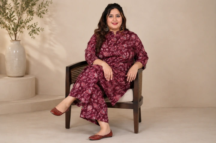 Woman seated confidently in a maroon floral hand-block printed kurta set from Attiris's 3XL to 8XL collection